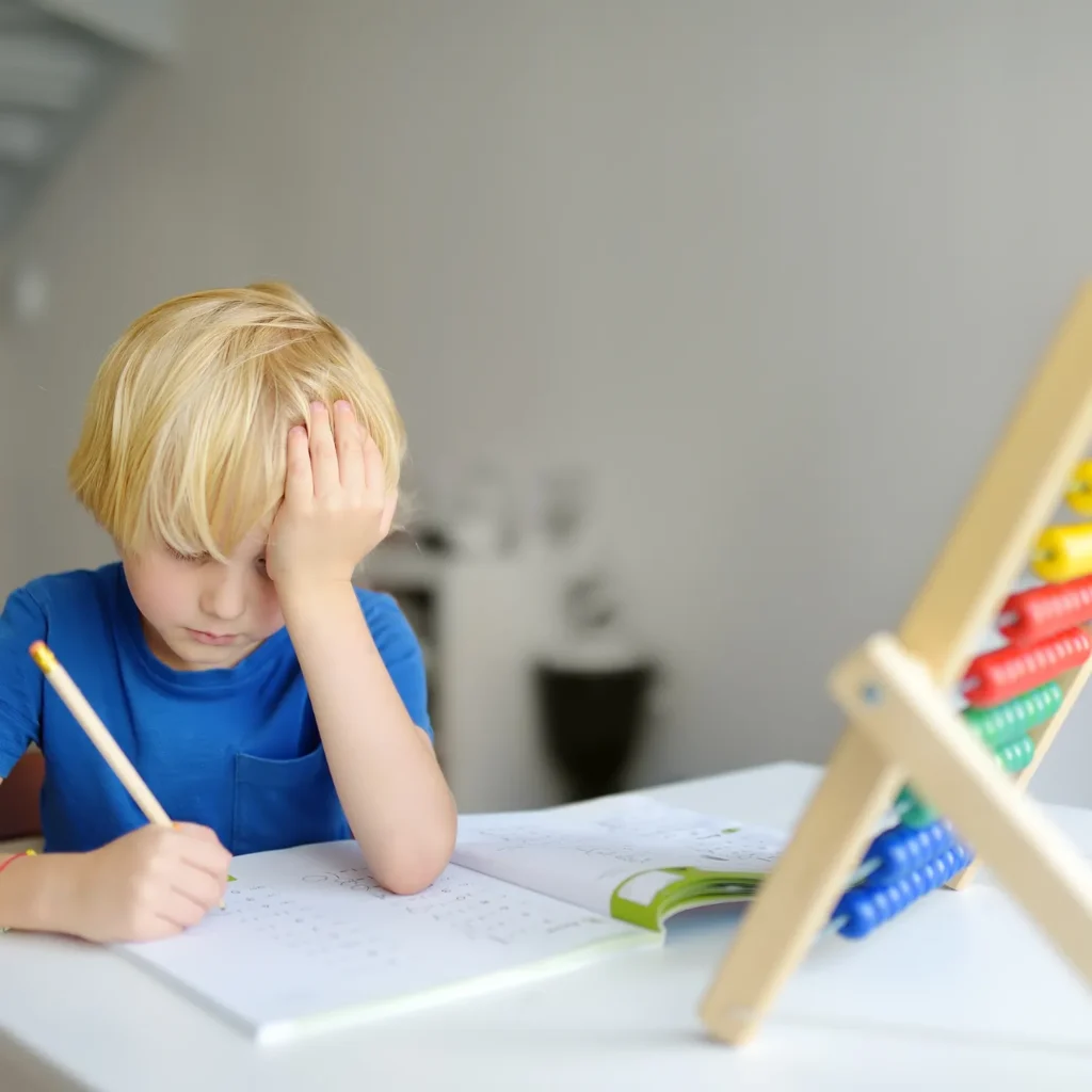 Niño con TDAH escribiendo en un cuaderno, con signos de dificultad atencional, en consulta de neuropsicología en Murcia