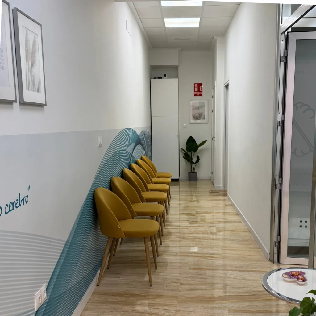 Sala de espera de clínica de neuropsicología en Murcia, Neuroien, con sillas color mostaza y mesa de recepción